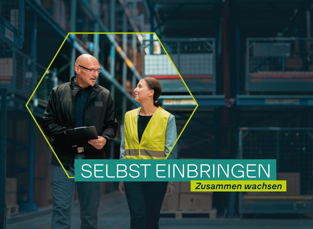 Zwei Mitarbeitende der VOLKSWAGEN GROUP OTLG gehen gemeinsam durch ein Logistiklager und sprechen miteinander